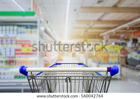 Supermarket aisle with empty blue shopping cart
