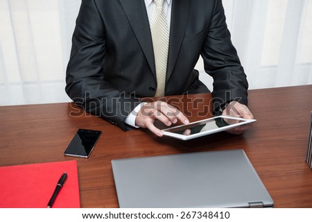 The manager working in the office at a desk on a tablet computers. In the office and office equipment