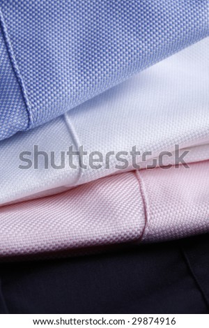 textile background - white, pink and light blue business shirts stacked - plenty of copy-space