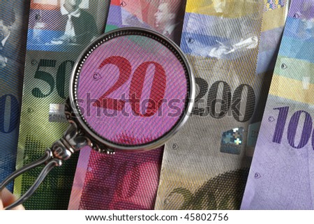 Swiss bank bills with magnifying glass