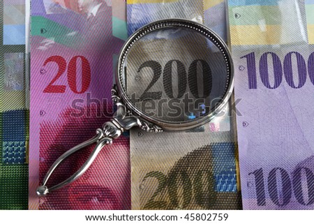 Swiss bank bills with magnifying glass