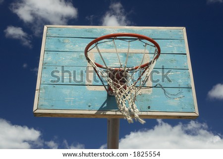 Basketball hoop and net against blue sky with clouds.