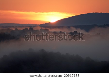 Misty morning of hilly area with ray of light. Russia, Ural.