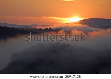 Misty morning of hilly area with ray of light. Russia, Ural.