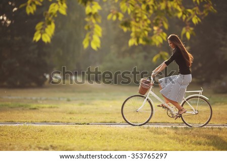 Beautiful smiling girl is riding the bicycle in the park