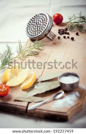 Cooking fish: kitchen utensils, spices and herbs for peeling and cooking fish, on wooden cutting board