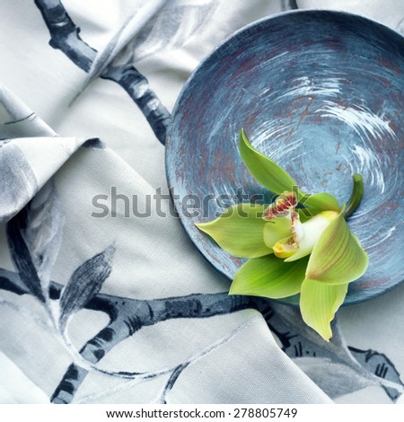 Orchid flower set against a grey printed fabric, age defying beauty concept