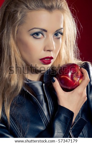 Sensual blond girl wearing a leather jacket offering an apple
