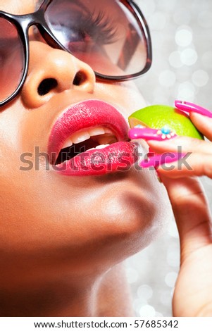 Sensual tanned woman eating a slice of lime