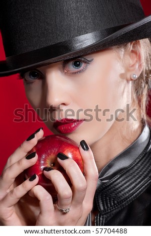 Sensual blond girl wearing a hat, offering an apple
