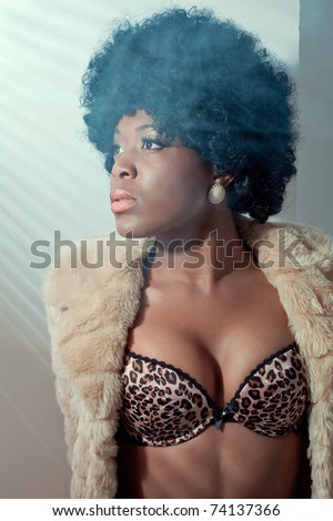 Young beautiful black woman wearing a fur coat and sexy lingerie