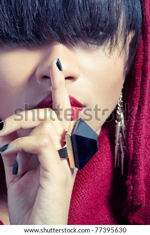 Closeup picture of young woman with finger on red lips, signaling to keep secret