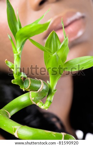 Beautiful woman\'s face with bamboo leaves, closeup shot, focus on the bamboo