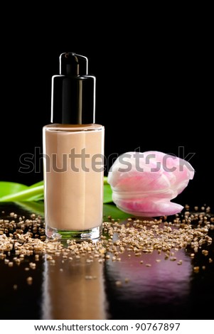 Closeup shot of foundation cream with a flower, isolated on black