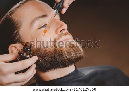 Oil for beard in dropper, process of moisturizing hair.