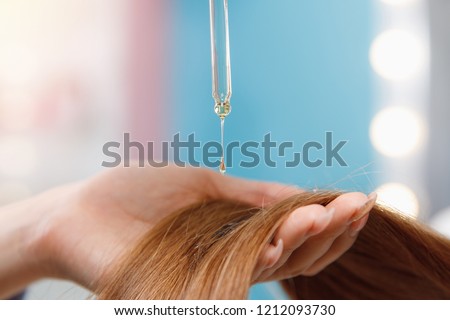 Close-up drop of oil restore and recovery hair is applied to head bulbs. Concept hairdresser spa salon.