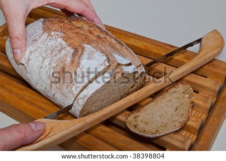 Slicing an wood stove baked organic artisan loaf of kamut flour bread on a bread board with knife