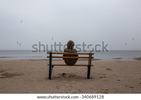 Loneliness teenager sitting on a bench at the sea shore
