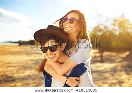 young beautiful loving couple in hipster fashion style posing on a Sunny beach in the shirt t-shirt baseball cap and sunglasses, happily smiling and laughing. outdoor close up portrait