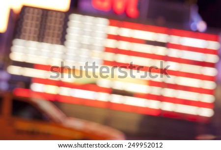 blurred street lights of neon US flag and yellow cab at Times Square in New York City in the night, abstract background