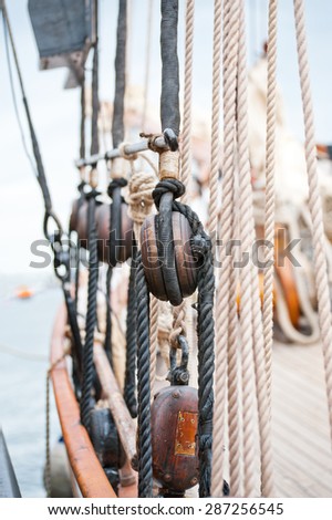 Marine ropes and tackles on the tall ship. Old wooden block with rope on the sail.