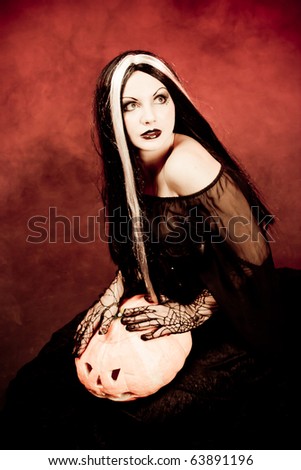 Portrait Halloween witch with a pumpkin. Red smoke background