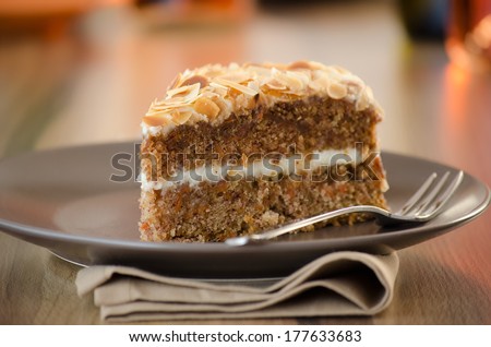 Slice of carrot cake with cheese cream frosting and almonds flakes