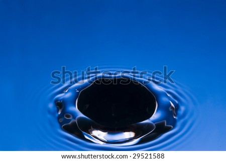 black hole produced by a falling droplet on a blue water surface