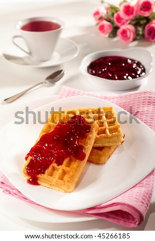 Belgian waffles, red fruits jam and tea breakfast composition
