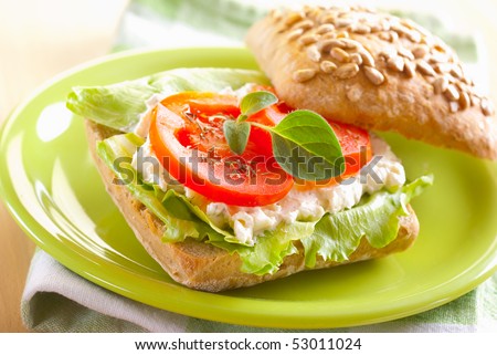 roll sandwich with cream cheese, tomato and salad on a plate