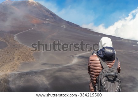 Male photographer taking pictures of Mount Etna in clouds, view from behind