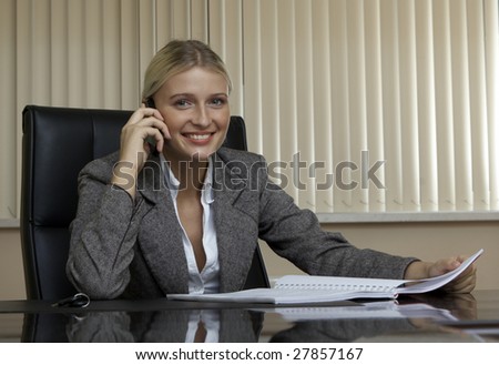 Business woman in cabinet at the table talks on telephone