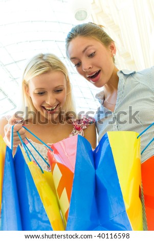 Two women with bags at shopping looking in the bag.