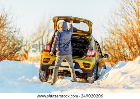 Car and man on snowy road in countryside