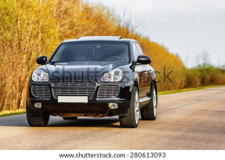 Black luxury car at byroad in autumn time