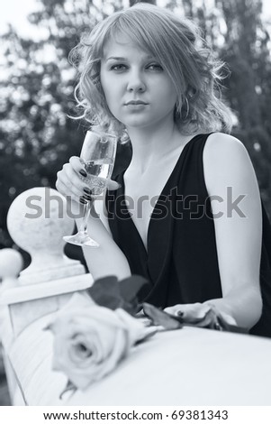Beautiful woman drinking champagne from wineglass in black and white with soft blue tint
