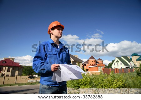 Man in a helmet with the plan of construction and on a background of buildings