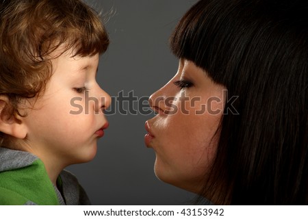 Mother was kissing her little son, son looking on lips