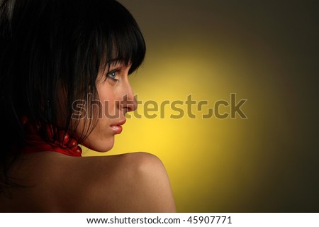 Beautiful girl is standing backwards and looking to the right, yellow light on background