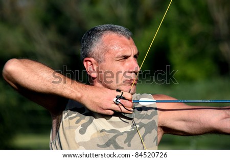Portrait of professional bowman aiming with bow and arrow