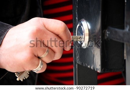 Hand with keys unlocking the front door, outdoor