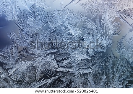 beautiful festive frosty pattern with white snowflakes on a blue background on glass