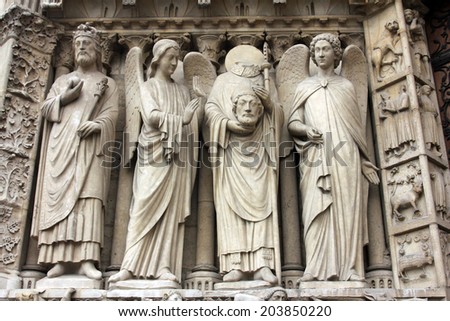 PARIS, FRANCE - NOV 05, 2012: Emperor Constantine, angel, St Denis holding his head, and angel, detail of Notre Dame cathedral. The Portal of the Virgin, dedicated to the patroness of the cathedral.
