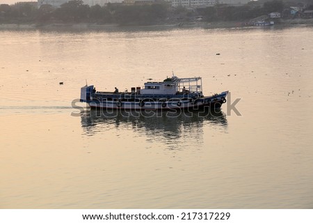 KOLKATA, INDIA - FEBRUARY 08:Old ferry boat crosses the Hooghly River nearby the Howrah Bridge on February 08, 2014. To use the ferry is easy, fast and cheap way how to cross the Hooghly River.