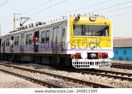 KOLKATA, INDIA - FEBRUARY 09: Unidentified locals and tourists commute by train on February 15, 2014 in Kolkata, India. Commuters on a busy train seek the breeze by an open doorway.