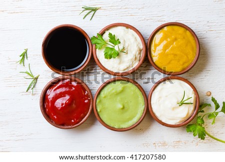 Sauces ketchup, mustard, mayonnaise, wasabi, soy sauce in clay bowls on wooden white background