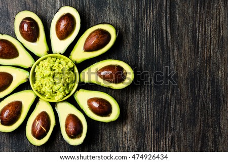 Avocado. Flower made from avocado palta and guacamole bowl on dark background. Guacamole ingredients. Healthy fat, omega 3. Half of avocado. Avocado tree. Top view. Copy space