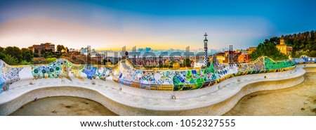 Mosaic tile panorama and Barcelona cityscape in famous park Guell at summer sunset,Spain