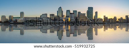Panorama of Canary Wharf business district with water reflection at sunset