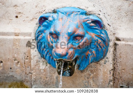 Close up on metal lion head pouring water - fountain in Paris, France